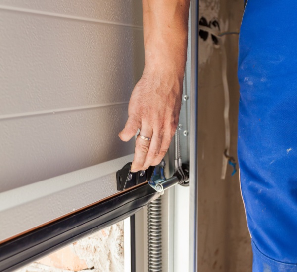 Technician fitting a replacement wood panel section on an older garage door