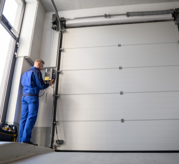Technician repairs industrial garage door in a modern workshop during daylight hours